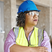 Woman in blue hard hat and yellow safety vest on construction jobsite