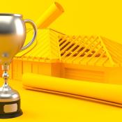 Trophy next to framed house and floor plans against bright yellow background