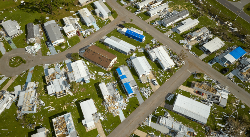 Aerial view of storm-damaged homes, some with blue roof tarps