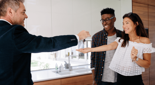 Salesman handing over keys after selling a new-construction home to a young couple