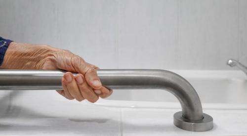 Elderly person gripping grab bar in bathroom